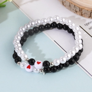 Gros plan des bracelets de couple en perles et perles noires avec des accents de cœur rouge