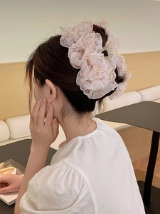 Grande molletta per capelli in organza floreale con fiocco indossata su uno chignon