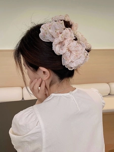 Dettaglio di una grande pinza per capelli rosa a fiori in organza su capelli raccolti