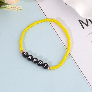 Detail of yellow seed bead bracelet featuring black happy letter beads and gold accents