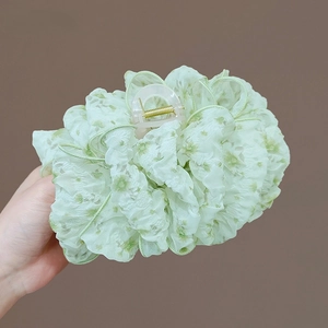 Dettaglio di un grande fermaglio per capelli con pizzo floreale verde chiaro e fiocco