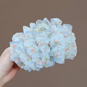 Dettaglio macro della pinza per capelli con fiocco multistrato in chiffon a fiori blu