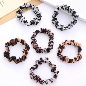 Detailed flat lay view of six leopard print satin scrunchies in assorted earth tones