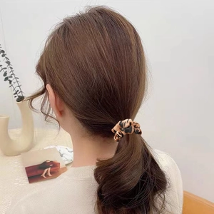 Satin leopard print hair scrunchie shown on a ponytail in a minimalist lifestyle setting