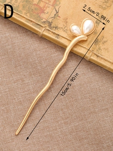 Détail d'un pic à cheveux doré vintage de 15 cm avec perles en forme de cœur sur lin