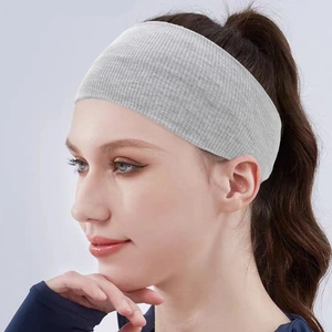Detail of light grey knitted elastic headband showing fine ribbed texture on model