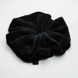 Close-up of fluffy black plush scrunchie showing soft texture and detailed stitching