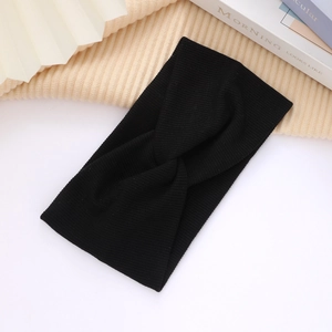 Close-up of black ribbed knit headband with cross knot design on neutral textured surface
