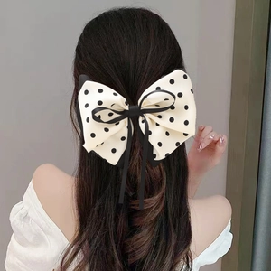 Elegante fermaglio per capelli con fiocco crema a pois neri su un'acconciatura da donna