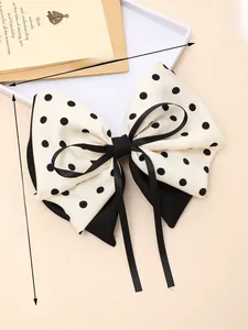 Dettaglio del fiocco in raso a pois con misure 19cm x 21cm su una scrivania beige