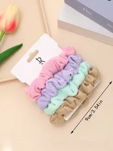 Detail of four colorful plush scrunchies showing fine pleated texture and elastic material
