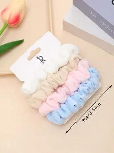 Detail of 4-piece plush scrunchie set in white, beige, pink, and blue on display card