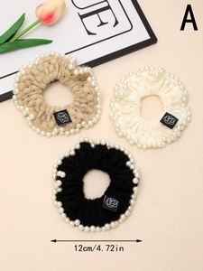 Close-up of three knitted lace scrunchies with white pearls in beige, cream, and black