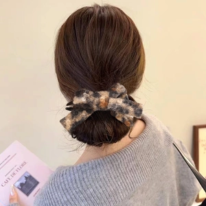 Leopard print plush bow hair claw clip for women securing a half-up bun hairstyle