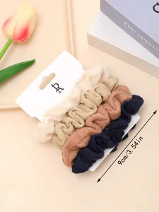 Set of four plush scrunchies in neutral tones displayed on a minimalist white card
