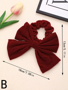 Macro detail of large burgundy velvet bow hair tie with 18cm dimension and soft texture