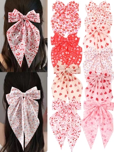 Detailed view of oversized satin bow hair clips with red heart and lip prints