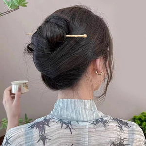 Spilla per capelli dorata con nappa e piccoli orecchini a cerchio per acconciatura classica