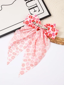 Close-up of pink satin bow hair clip with red lip prints and metal spring fastener