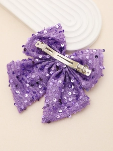 Detailed macro view of large purple sequined bow hair clip with silver metal alligator grip