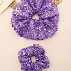 Lot de deux chouchous à paillettes violettes en tailles grande et moyenne sur fond beige