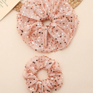 Vue détaillée de deux chouchous roses à paillettes avec tissu en maille et bande élastique