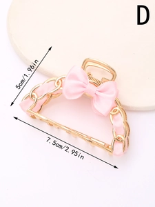 Detail view of pink satin ribbon woven through a gold alloy hair claw clip with bow