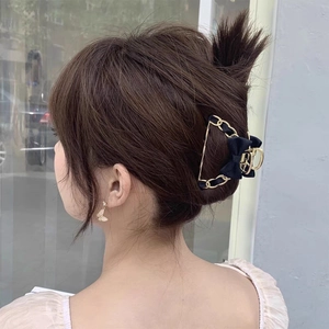 Elegant gold metal hair claw clip with black fabric bow and chain detail for women