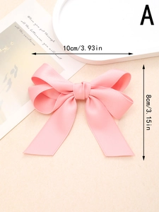 Détail de la pince à cheveux nœud en satin rose avec dimensions 10cm x 8cm sur fond beige