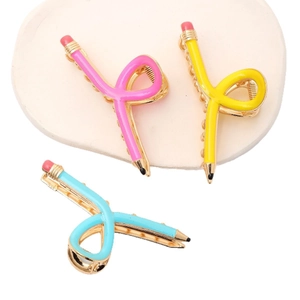 Trois pinces à cheveux en forme de crayon rose jaune et bleu sur un plateau blanc