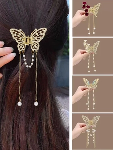 Dettaglio dei fermagli per capelli a farfalla dorata con zirconi e nappe di perle