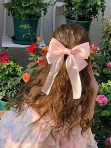 Makroaufnahme einer doppellagigen rosa Organza-Haarspange mit Schleife, getragen im Garten