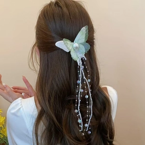 Dettaglio del fermaglio a farfalla in rete verde menta con perle e lunghe nappe di perline