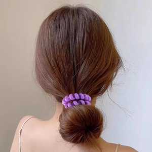 Bright purple spiral telephone cord hair tie shown on a low ponytail hairstyle