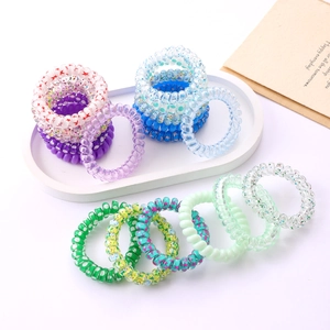 Detailed macro view of multi-colored spiral telephone wire hair ties in a tray