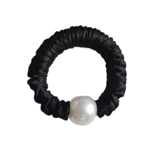 Detailed close-up of a black pleated satin hair scrunchie with a large white pearl bead