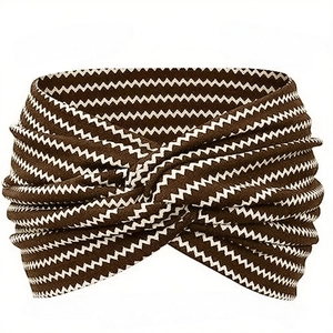 Détail d'un bandeau bohème en tricot avec rayures marron en zigzag et nœud torsadé devant