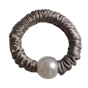 Detail of grey satin scrunchie with a large white pearl bead on a clean white background