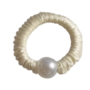 Detail of a cream satin scrunchie featuring a large glossy pearl accent and elastic band