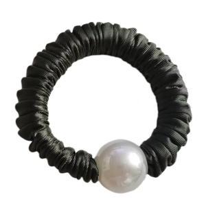 Detail of silk texture scrunchie with a large white pearl bead on black fabric
