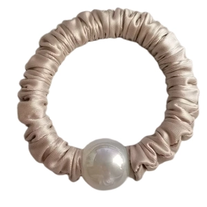 Close-up of champagne silk scrunchie with a large iridescent pearl accent detail