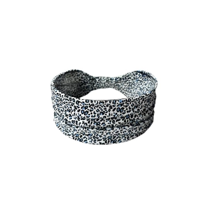 Detail view of leopard print elastic headband with blue and black spots on white fabric