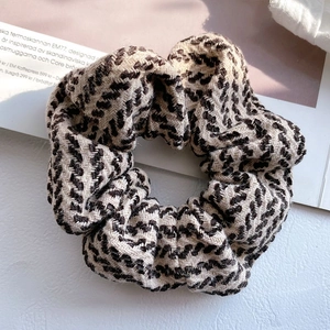 Close-up of a thick knitted scrunchie with a retro black, white, and brown chevron pattern