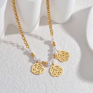 Détail de la chaîne en or 18 carats avec perles blanches et pendentifs roses ajourés