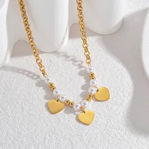 Détail du collier chaîne en or 18 carats avec perles blanches et trois pendentifs cœur