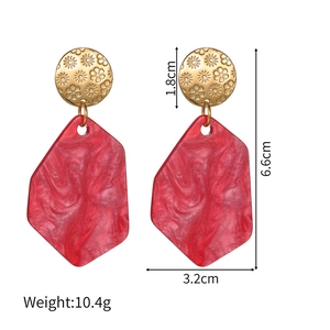 Detail view of red marble acrylic geometric earrings with embossed gold flower studs