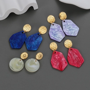 Detailed macro view of four pairs of colorful acrylic drop earrings with gold-plated sun patterns