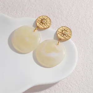 Detailed close-up of retro geometric earrings with marbled resin discs and starburst studs