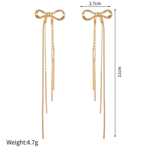 Detail view of gold bow earrings showing 11cm long metal tassel chains and sizing info