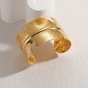Polished gold feather C-shape open bangle with detailed metallic texture and wide design